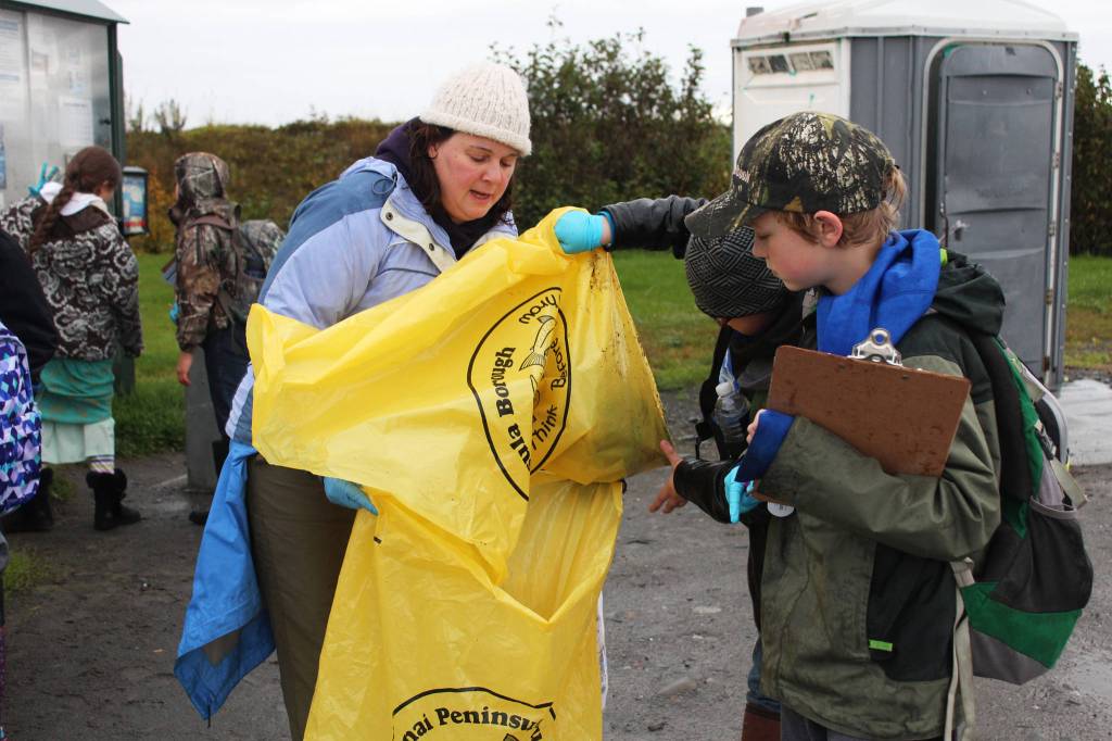 Kendall Dellasperanza, a teacher at McNeil Canyon Elementary School, helps some of her fourth grade students transfer trash from one bag to another Friday, Sept. 22, 2017 during the Kachemak Bay CoastWalk at Mariner Park in Homer, Alaska. Citizen groups, including classes from multiple schools, adopt a section of Kachemak Bay shoreline to clean up during the annual event hosted by the Center for Alaskan Coastal Studies. (Photo by Megan Pacer/Homer News.)