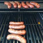 This Sept. 17, 2017 photo shows bratwurst sausages being grilled before simmering in beer in Houston. This dish is from a recipe by Elizabeth Karmel. (Elizabeth Karmel via AP)