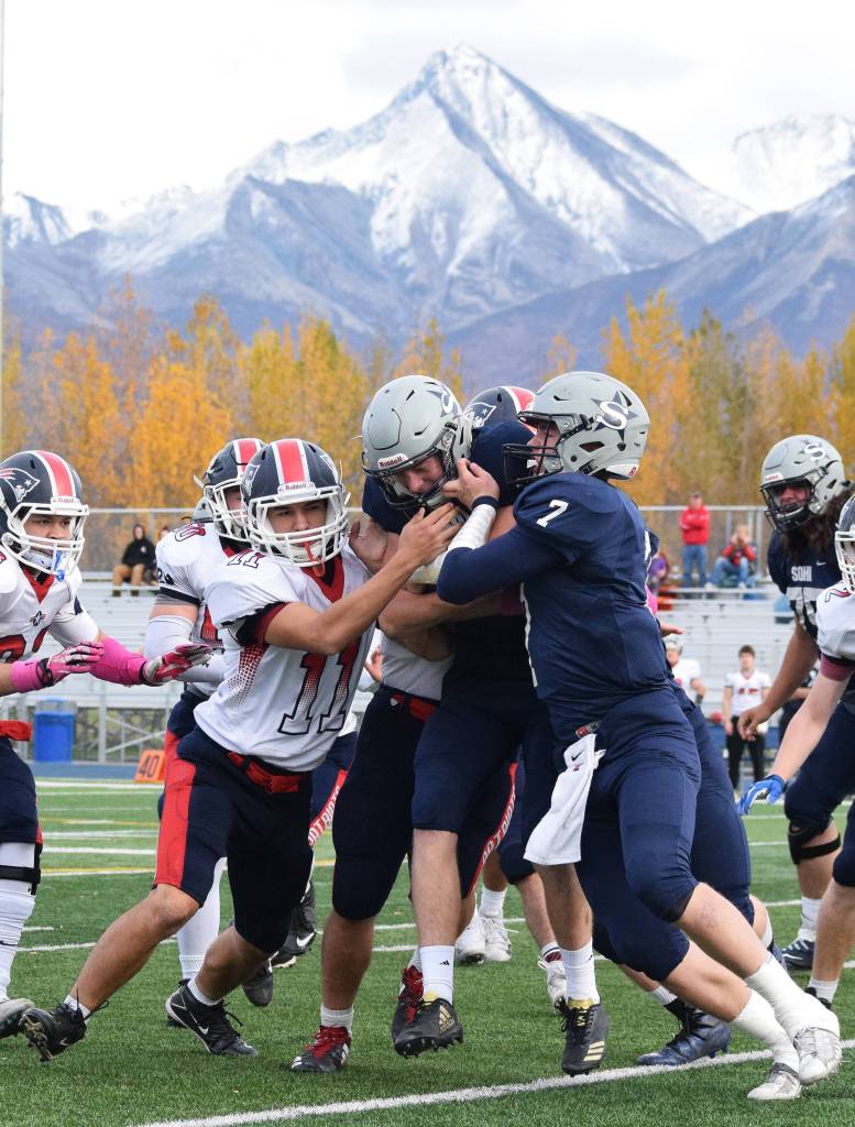 Soldotna running back Cody Quelland receives a push from teammate Brandon Crowder (7) against North Pole defender Devan Drumhiller (11) and others Saturday at the ASAA First National Bank state football semifinals at Palmer High School. (Photo by Joey Klecka/Peninsula Clarion)
