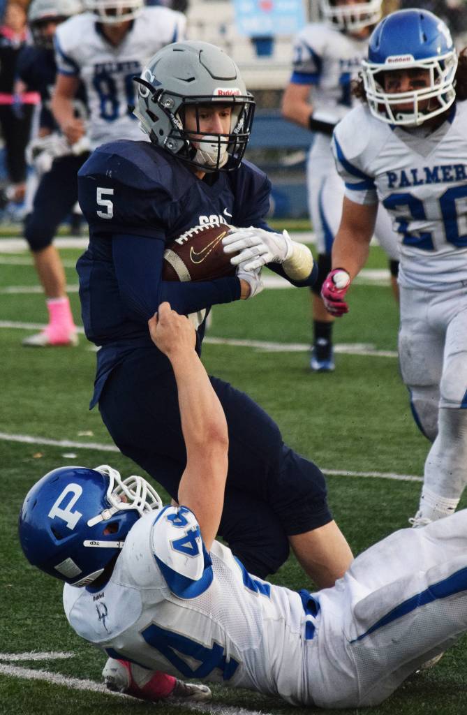 Soldotna senior Luke Trammell (5) works to stay standing as Palmer defender Dylan Myers attempts to tackle him Saturday in the ASAA First National Bank Division II state championship at Machetanz Field in Palmer. (Photo by Joey Klecka/Peninsula Clarion)