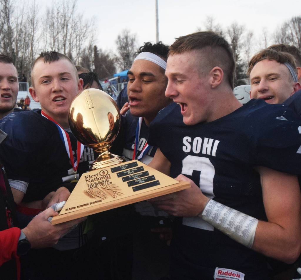 (From left to right) Brenner Furlong, Wendell Tuisuala and Cody Quelland celebrate Saturday with the ASAA First National Bank Division II state championship trophy at Machetanz Field in Palmer following a 21-0 victory over the Palmer Moose. (Photo by Joey Klecka/Peninsula Clarion)