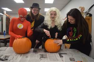 Tori Giles, left, Emilie Grimes, Torile Giles and Arin Reger carve pumkings at the Soldotna Public Library on Saturday, October 21, 2017 during the library&rsquo;s teen halloween party. The group donned costumes from The Flash, including The Flash, Killer Frost and Harrison Wells. (Photo by Kat Sorensen/Peninsula Clarion)