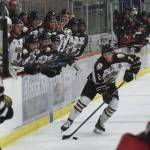 Kenai River Brown Bears defenseman Markuss Komuls (2) looks for an open teammate Friday night with a crowd of teammates cheering him on against the Minnesota Magicians at the Soldotna Regional Sports Complex. (Photo by Joey Klecka/Peninsula Clarion)