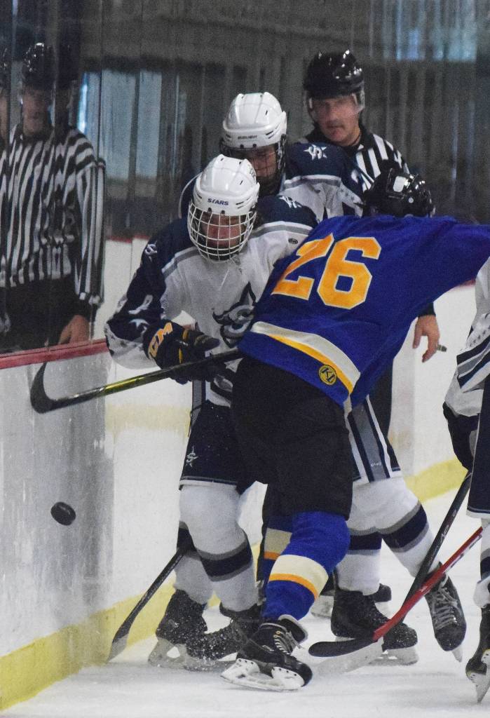 Monroe Catholic&rsquo;s Jacob Rauenhorst (26) checks Soldotna&rsquo;s J.D. Schmelzenbach into the boards Thursday at the Peninsula Ice Challenge at the Soldotna Regional Sports Complex. (Photo by Joey Klecka/Peninsula Clarion)