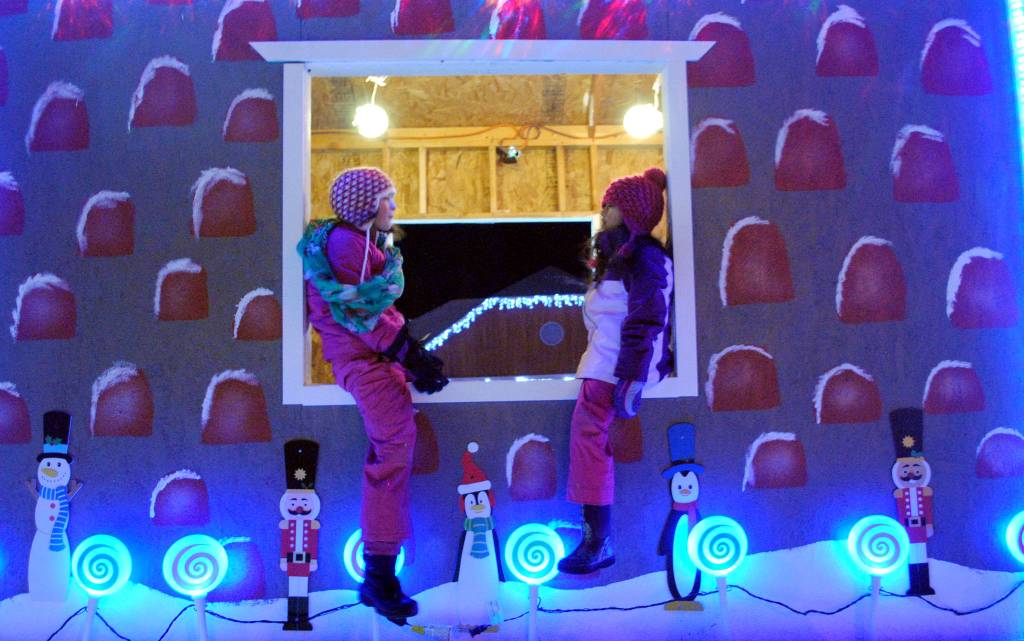 Sienne Lautarette, left, and Emma Glassmaker welcomed Christmas to Kenai at Friday night&rsquo;s Christmas Comes to Kenai celebration at the Kenai Visitor Center. The evening festivities included an electric light parade, a fireworks show and snacks. Although a bonfire was planned, high winds prevented the piles of pallets from being lit. (Photo by Kat Sorensen/Peninsula Clarion)