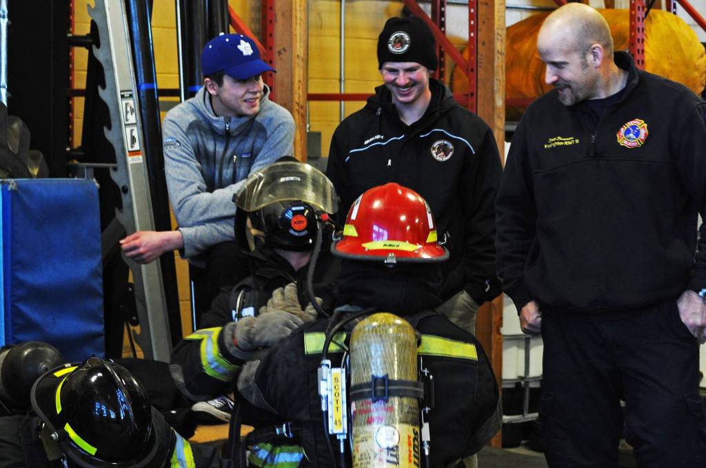 Two Kenai River Brown Bears players, blinded by blackout firefighting training masks, feel in the dark for each other during a tour and training demonstration at the Kenai Emergency Operations Center on the Kenai Municipal Airport on Tuesday, Nov. 28, 2017 in Kenai, Alaska. Kenai Fire Department firefighters walked the Brown Bears players through some of the training and tools firefighters use to give them an idea of what a career in fire response is like. (Photo by Elizabeth Earl/Peninsula Clarion)