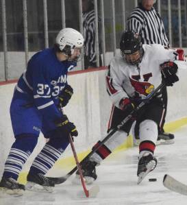 Kenai Central skater Jacob Keels scrambles to find the puck in front of Palmer&rsquo;s Noah Keil, Friday at the Kenai Multipurpose Facility. (Photo by Joey Klecka/Peninsula Clarion)