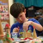 Gabriel Dravis sticks a gumdrop on to the gingerbread house he built from graham crackers, frosting, and candy in Stacy Tronnier’s first and second grade class at Kaleidoscope School of Arts and Science on Friday, Dec. 15 in Kenai, Alaska. Three first and second grade classes at Kaleido- scope made gingerbread houses on Friday to take home for display and/or eating. (Photo by Ben Boettger/Peninsula Clarion)
