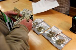 In this Jan. 1, 2018 file photo, a customer purchases marijuana at the Harborside marijuana dispensary in Oakland, Calif., on the first day that recreational marijuana was sold legally in California. In January 2018, Attorney General Jeff Sessions rescinded a 2013 Obama Administration policy pledging that federal authorities would not crack down on marijuana operations in states where they were legal as long as the states maintained tight regulations. (AP Photo/Mathew Sumner)