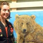 Artist Julianne Tomich stands next to one of her bear paintings at the First Friday opening of her show at Grace Ridge Brewery. (Photo by Michael Armstrong, Homer News)