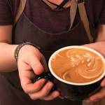 Barrista Hallie Riddall holds a latte into which she poured the design of a pine needle cluster on Saturday, Jan. 13, 2018 at Kaladi Brothers Coffee in Soldotna. (Ben Boettger/Peninsula Clarion).