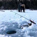 Some of the tools for ice fishing, including a rod, holder and auger, are seen here during a trip fishing on Spirit Lake Dec. 26, 2017, while other anglers continue to set up their rigs to fish. (Photo by Kat Sorensen/Peninsula Clarion)
