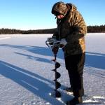LEFT: Jon Watson, pastor at Peninsula Christian Center of Soldotna and avid ice fisherman, drills a series of holes in the ice on Sprit Lake. The ice was about eight inches deep.