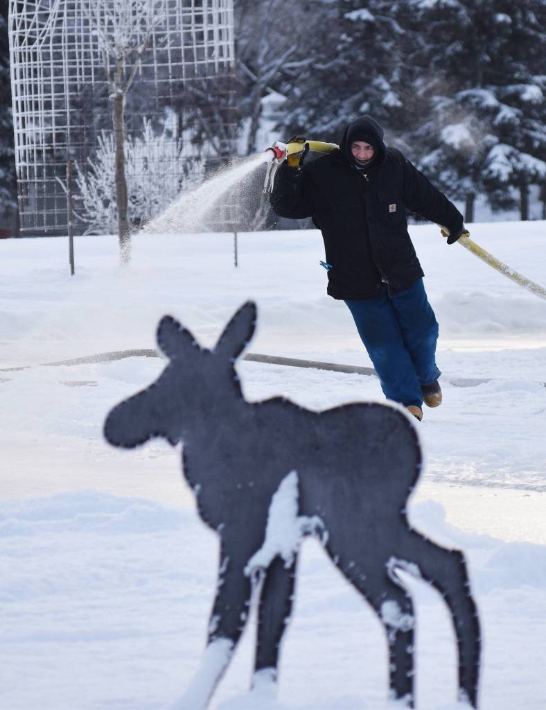 A Soldotna Parks & Recreation worker sprays a layer of water to be frozen into a skating rink Thursday at Soldotna Creek Park. (Photo by Joey Klecka/Peninsula Clarion)