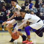 Nikiski junior Cody Handley (center) dives for the ball with Monroe&rsquo;s Gavin Jackson (right) Friday night at the Rus Hitchcock Nikiski Tip-Off Tournament in Nikiski. (Photo by Joey Klecka/Peninsula Clarion)