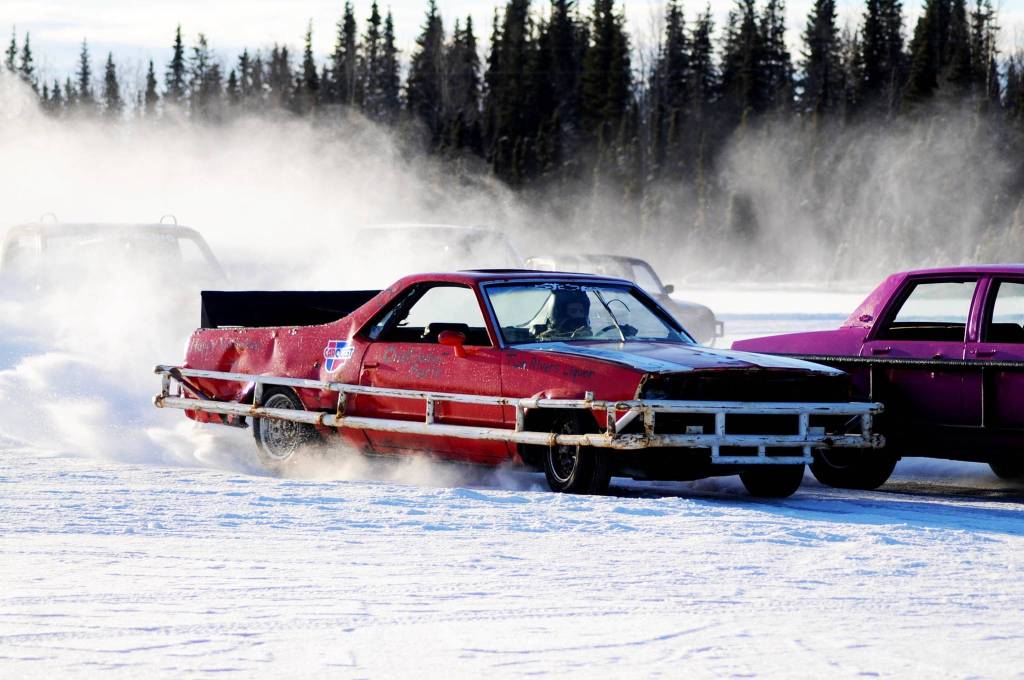 A racecar driver passes the crowd of competitors on the ice track atop a frozen lake at the Decanter Inn on Sunday, Jan. 22, 2018 in Kasilof, Alaska. Every Sunday in the winter, the Decanter Inn hosts Peninsula Ice Racing events for drivers to try their hand at the frozen track on the shallow lake at the bottom of the hill behind the inn. The racers can use studded tires on their front wheels only and equip the sides of their vehicles with bumpers as other vehicles are likely to slip and slide into them. Spinning out is common. A tow truck waits on the sidelines to retrieve drivers who get stuck on the berms alongside the track. Fans gathered Sunday despite the cold to cheer the racers on. The men race in the morning, followed by the women&rsquo;s races in the afternoon. (Photo by Elizabeth Earl/Peninsula Clarion)