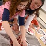 Jenny Gates, right, of Alaska Department Fish and Game leads Aliya Blough through a salmon dissection at the Connections Homeschool office in Soldotna on Thursday. (Photo by Kat Sorensen/Peninsula Clarion)