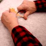 Margaret Quinn of Kenai carves details into a chickadee magnet during a whittling class at the Kenai Senior Center in Kenai on Tuesday. (Photo by Kat Sorensen/Peninsula Clarion)