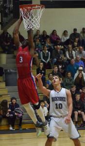 ACS forward Frederick Onochie lays in a bucket over Nikiski&rsquo;s Ian Johnson (10) Friday at Nikiski High School. (Photo by Joey Klecka/Peninsula Clarion)