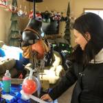 A woman inspects one of the entries in the Way Out Women fundraiser&rsquo;s Wild and Wooly Bra contest &mdash; a steampunk bra complete with whirling tassles on Saturday, Feb. 24, 2018 near Ninilchik, Alaska. (Photo by Erin Thompson/Peninsula Clarion)