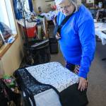Kathy Lopeman, founder of the Way Out Women snowmachine ride fundraiser, shows off a quilt offered for auction at the Saturday, Feb. 24, 2018 event in the Caribou Hills near Ninilchik, Alaska. (Photo by Erin Thompson/Peninsula Clarion)