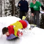 Boone Theiler wipes out during a sled race at the Boys and Girls Club in Kenai for the Police Athletic League Club on Monday. The club is a sports-oriented opportunity for youth and law enforcement to interact and organizers set-up an Olympics inspired day where the kids competed for medals in different winter activities. (Photo by Kat Sorensen/Peninsula Clarion)