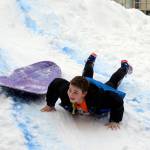Makai Johansen wipes out during a sled race at the Boys and Girls Club in Kenai for the Police Athletic League Club on Monday. The club is a sports-oriented opportunity for youth and law enforcement to interact and organizers set-up an Olympics inspired day where the kids competed for medals in different winter activities. (Photo by Kat Sorensen/Peninsula Clarion)