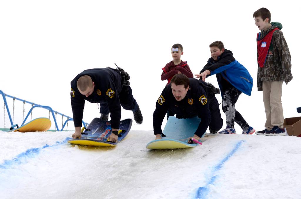 Patrol Officer Josh Hall, left, and School Resource Officer Dan Smith take a turn sledding down the Olympic course set up for the Boys and Girls Club&rsquo;s Police Athletic League (P.A.L.) Club in Kenai on Monday. The club is a sports-oriented opportunity for youth and law enforcement to interact and organizers set-up an Olympics inspired day where the kids competed for medals in different winter activities. (Photo by Kat Sorensen/Peninsula Clarion)