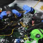 Kassidy Stock (right) of the Nikiski Fire Department signals diving partner Matt Quiner (left) to dive through a hole in the ice on Island Lake as part of a diving training drill Friday, March 9, 2018 in Nikiski, Alaska. The Nikiski Fire Department is working on getting its ice diving team up to certifications to perform operations on frozen lakes if need be, such as rescuing sunken cars or people or recovering evidence. (Photo by Elizabeth Earl/Peninsula Clarion)