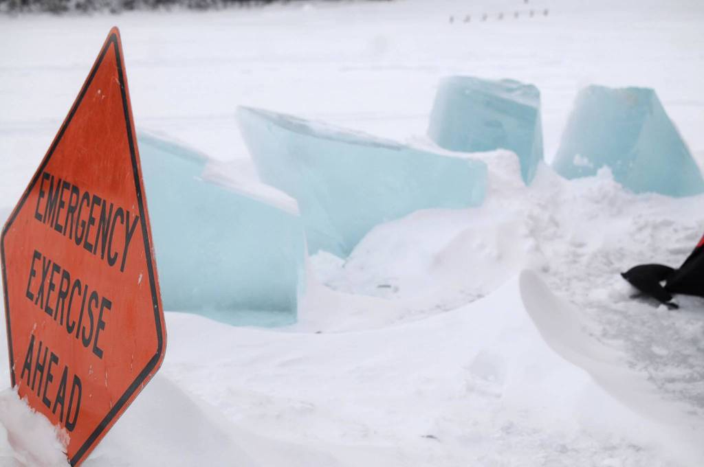 Three-foot high blocks of ice sit on the frozen surface of Island Lake near a sign warning the public that the Nikiski Fire Department is conducting an ice diving drill on Friday, March 9, 2018 in Nikiski, Alaska. The Nikiski Fire Department is working on bringing all the members of its ice diving team up to proper certifications. To attain full certifications, divers have to clock a number of hours in the water, including practicing beneath the ice. (Photo by Elizabeth Earl/Peninsula Clarion)