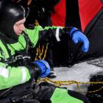 Matt Quiner of the Nikiski Fire Department checks his gear before dropping through a hole in the ice covering Island Lake as part of a training drill Friday, March 9, 2018 in Nikiski, Alaska. The Nikiski Fire Department is working on bringing all the members of its ice diving team up to proper certifications. To attain full certifications, divers have to clock a number of hours in the water, including practicing beneath the ice. (Photo by Elizabeth Earl/Peninsula Clarion)