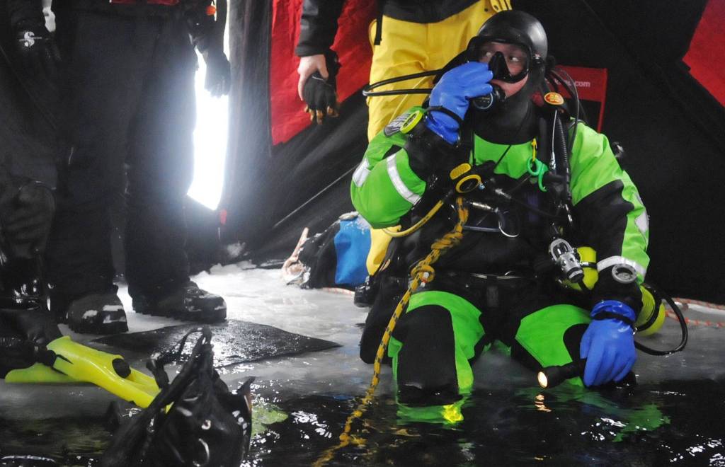 Kassidy Stock of the Nikiski Fire Department prepares to drop through a hole in the ice covering Island Lake as part of a training drill Friday, March 9, 2018 in Nikiski, Alaska. The Nikiski Fire Department is working on bringing all the members of its ice diving team up to proper certifications. To attain full certifications, divers have to clock a number of hours in the water, including practicing beneath the ice. (Photo by Elizabeth Earl/Peninsula Clarion)