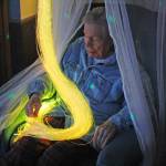 A resident at Heritage Place enjoys colored strands of light during an open house of the home&rsquo;s Snoezelen room on Friday, March 23 in Soldotna. (Photo by Erin Thompson/Peninsula Clarion)