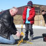 Scott Aleckson (left) clips wires to the ignition contacts of a model rocket while students at his model rocketry session observe in the parking lot of the Soldotna Regional Sports Complex in Soldotna, Alaska on Saturday, May 31, 2018. Aleckson said he made and launched his first plastic, balsa wood, and cardboard rocket as a 4th grade student at Soldotna Elementary School. Since then he&rsquo;s built a custom launch system, he said, &ldquo;with recycled electronics and a lot of soldering time.&rdquo; Aleckson taught Saturday&rsquo;s rocketry class through the Soldotna Community Schools program, and said he&rsquo;d like to continue spreading the hobby. &ldquo;If I could get a model rocket club going, that&rsquo;d be great,&rdquo; he said. &ldquo;Stuff like this is much more fun in a group.&rdquo; (Photo by Ben Boettger/Peninsula Clarion)
