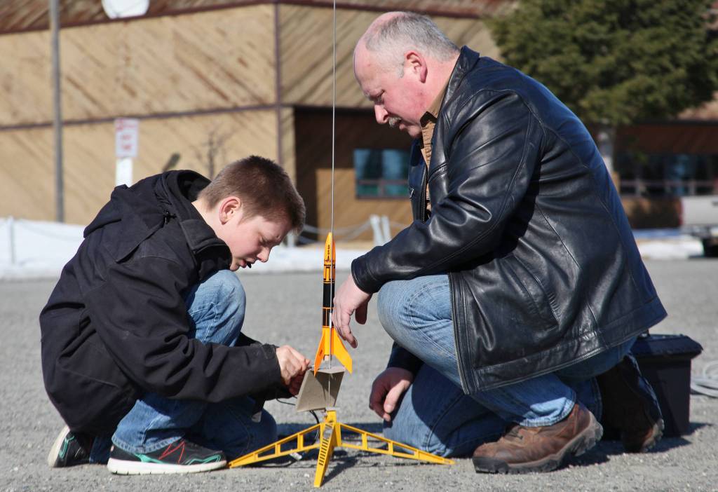 Asa Lorentzen (left) clips wires to ignition contacts while model rocketry instructor Scott Aleckson observes in the parking lot of the Soldotna Regional Sports Complex in Soldotna, Alaska on Saturday, May 31, 2018. Aleckson said he made and launched his first plastic, balsa wood, and cardboard rocket as a 4th grade student at Soldotna Elementary School. Since then he&rsquo;s built a custom launch system, he said, &ldquo;with recycled electronics and a lot of soldering time.&rdquo; Aleckson taught Saturday&rsquo;s rocketry class through the Soldotna Community Schools program, and would like to continue spreading the hobby. &ldquo;If I could get a model rocket club going, that&rsquo;d be great,&rdquo; he said. &ldquo;Stuff like this is much more fun in a group.&rdquo; (Photo by Ben Boettger/Peninsula Clarion)