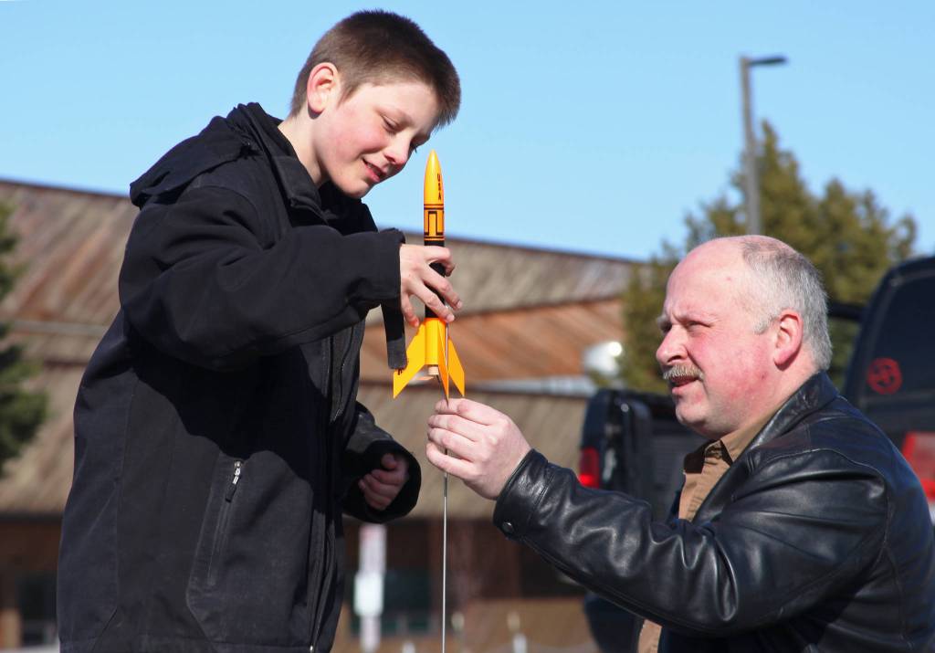 Asa Lorentzen (left) mounts a model rocket on its launch rod while instructor Scott Aleckson observes in the parking lot of the Soldotna Regional Sports Complex in Soldotna on Saturday. Aleckson said he made and launched his first plastic, balsa wood, and cardboard rocket as a 4th grade student at Soldotna Elementary School. Since then he&rsquo;s built a custom launch system, he said, &ldquo;with recycled electronics and a lot of soldering time.&rdquo; Aleckson taught Saturday&rsquo;s rocketry class through the Soldotna Community Schools program, and would like to continue spreading the hobby. &ldquo;If I could get a model rocket club going, that&rsquo;d be great,&rdquo; he said. &ldquo;Stuff like this is much more fun in a group.&rdquo; (Photo by Ben Boettger/Peninsula Clarion)