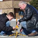 Asa Lorentzen (left) clips wires to ignition contacts while model rocketry instructor Scott Aleckson observes in the parking lot of the Soldotna Regional Sports Complex in Soldotna on Saturday. Aleckson said he made and launched his first plastic, balsa wood, and cardboard rocket as a 4th grade student at Soldotna Elementary School. Since then he&rsquo;s built a custom launch system, he said, &ldquo;with recycled electronics and a lot of soldering time.&rdquo; Aleckson taught Saturday&rsquo;s rocketry class through the Soldotna Community Schools program, and would like to continue spreading the hobby. &ldquo;If I could get a model rocket club going, that&rsquo;d be great,&rdquo; he said. &ldquo;Stuff like this is much more fun in a group.&rdquo; (Photo by Ben Boettger/Peninsula Clarion)