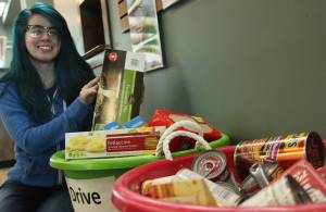 Youth Librarian Ali Jobe of the Joyce K. Carver Memorial Soldotna Public Library sits beside the canned goods and other nonperishable food items that library patrons have donated to the Kenai Peninsula Food Bank in lieu of late fees during the library&rsquo;s food for fines collection drive on Wednesday, April 11, 2018 in Soldotna, Alaska. In addition to the two and a half bins of food at the library entrance, the Food Bank has already recieved 193 pounds of food since the library began collecting on April 9. Soldotna librarians will take food for fines &mdash; at an exchange rate of $1 per item &mdash; until April 14. (Ben Boettger/Peninsula Clarion).