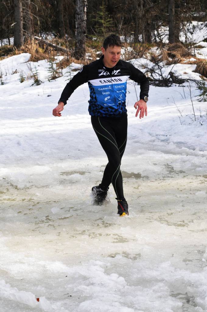 Jon Iannaccone runs through an icy puddle on the Wolverine Trail during the 2018 Choose Your Weapon race at Tsalteshi Trails on Sunday, April 15, 2018 in Soldotna, Alaska. Racers completed two 5-kilometer laps around the lower trails by running, biking or skiing, with the option of switching between laps for extra points. Most of the trails had some snow with patches of wet mud sprinkled throughout as spring temperatures begin to dominate the central Kenai Peninsula. (Photo by Elizabeth Earl/Peninsula Clarion)