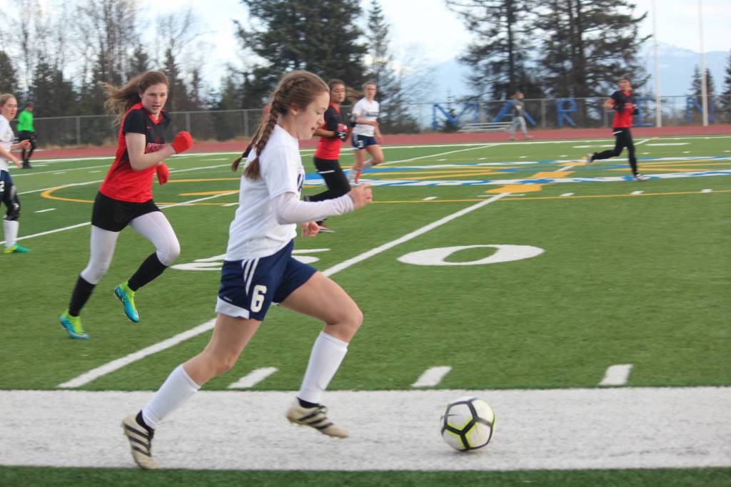Homer&rsquo;s Eve Brau takes the ball up the field pursued by Kenai High School&rsquo;s Abigail Every during their game against Tuesday, April 24, 2018 in Homer, Alaska. (Photo by Megan Pacer/Homer News)