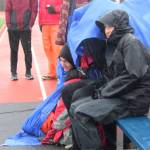Members of the Homer High School soccer team huddle under raincoats and tarps as hail pours down during their game against Kenai Central High School on Tuesday, April 24, 2018 in Homer, Alaska. (Photo by Megan Pacer/Homer News)