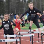 Nikiski teammates Kelsey Clark (left) and Bethany Carstens hurdle a barrier in the girls 300-meter hurdles Saturday at the Kenai Invitational at Ed Hollier Field. (Photo by Joey Klecka/Peninsula Clarion)