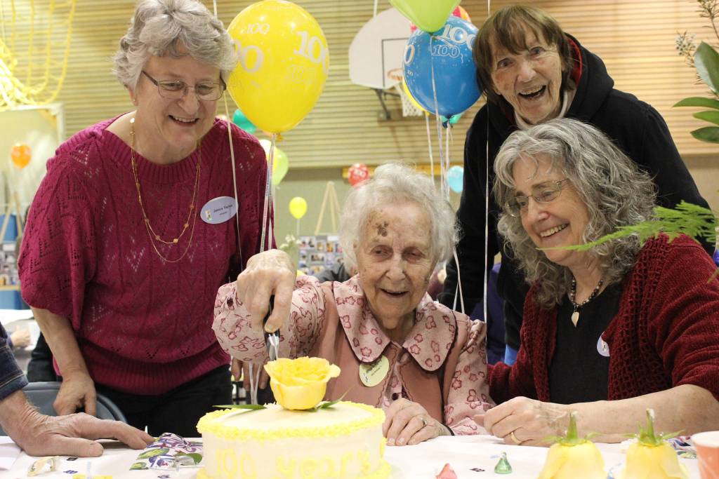 Wilma Gregory, center, cuts into a cake in celebration of her 100th birthday on Saturday. Helping are Gregory&rsquo;s daughters Janice Taylor of Juneau, left, and Gayle Forrest of Homer, right. Friend Randi Somers of Homer, back, looks on. (Photo by McKibben Jackinsky)