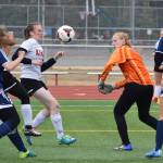 Homer goalkeeper Kelli Bishop (in orange) knocks the ball away on a Kenai Central rush Tuesday evening at Ed Hollier Field in Kenai. (Photo by Joey Klecka/Peninsula Clarion)