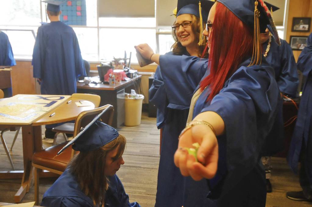 Kenai Alternative High School graduate Jessie Metz (left) zips up graduate Laura Archuleta&rsquo;s (right) graudation gown before the high school&rsquo;s graduation ceremony on Tuesday, May 22, 2018 in Kenai, Alaska. Kenai Alternative High School provides more flexible edcuation for students who struggled in traditional high school environments, scheduling classes around jobs, children and life circumstances to help students achieve their high school diplomas. (Photo by Elizabeth Earl/Peninsula Clarion)