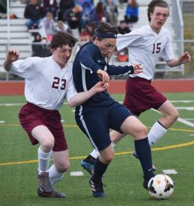 Homer midfielder Timothy Blakely (center) battles for the ball against Grace&rsquo;s Dylan Harris (23) and Luke Schaezlien Thursday in Division II soccer tournament play at Eagle River High School. (Photo by Joey Klecka/Peninsula Clarion)