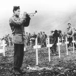 FILE - In this Aug. 1943 file photo, a bugler sounds taps during a memorial service while a group of G.I.s visit the graves of comrades who fell in the reconquest of Attu Island, part of the Aleutian Islands of Alaska. May 30, 2018 will mark the 75th anniversary of American forces recapturing Attu Island in Alaska&rsquo;s Aleutian chain from Japanese forces. It was the only World War II battle fought on North American soil. (AP Photo, File)