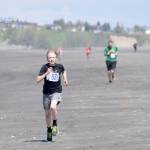 Jack Laker finishes off his victory in the three-mile run at the Mouth to Mouth Wild Run and Ride on Monday at the Kenai beach. (Photo by Jeff Helminiak/Peninsula Clarion)