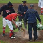 Twins players and coaches drop quick dry soil on the mound at Coral Seymour Memorial Ballpark, on a wet Friday afternoon in Kenai. (Photo by Joey Klecka/Peninsula Clarion)