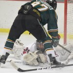 Kenai Kardinals goaltender Ryan Williams sprawls out to catch the puck under Colony forward Tristan Avoletta, Thursday night at the Kenai Multipurpose Facility. (Photo by Joey Klecka/Peninsula Clarion)